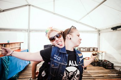 Eine Person breitet die Arme zu Flügeln, eine weitere Person umarmt sie von hinten